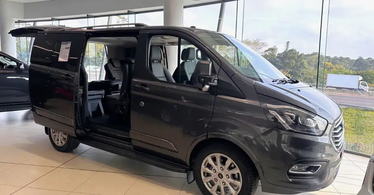 Black Ford Tourneo Custom 9-seater minibus with sliding door open in a car showroom