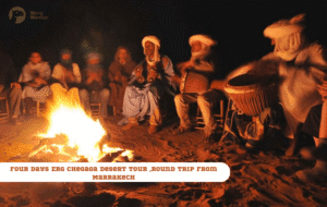 Merry Morocco tour card for Four Days Erg Chebbi Desert Tour Round Trip from Marrakech showing Berber musicians playing drums around a campfire at night
