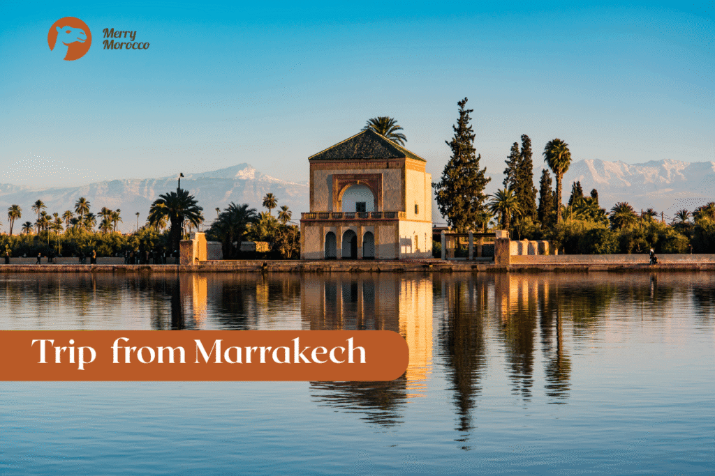 Merry Morocco Trip from Marrakech category card showing Menara Gardens pavilion reflected in the basin with snowy Atlas Mountains