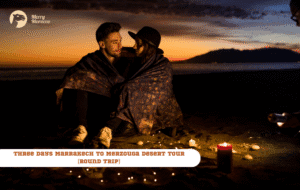 Merry Morocco tour card for Three Days Marrakech to Merzouga Desert Tour Round Trip showing a romantic couple wrapped in a blanket at sunset by the water